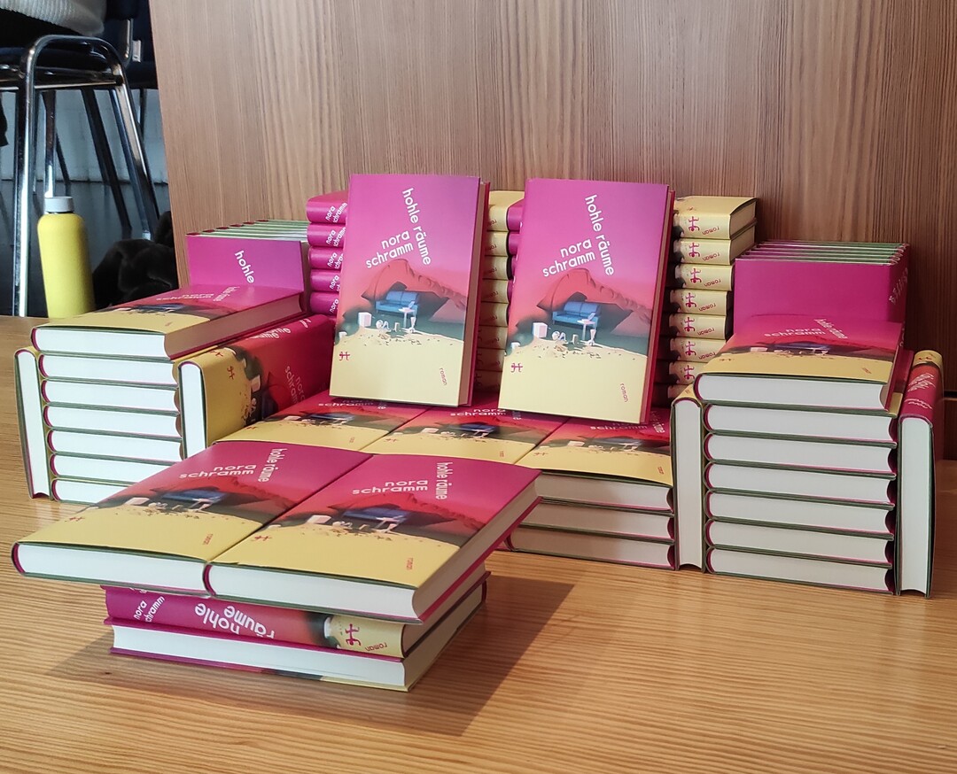 Buchstapel auf einem Tisch mit dem Buch "Hohle R&auml;ume" von Nora Schramm.